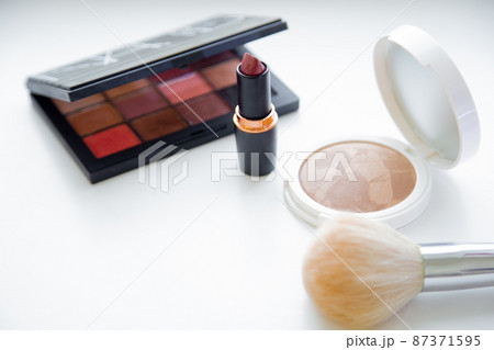 The white face powder and bronzer, black packaging with eye shadow, lipstick and brush lying on white background. High quality photo 87371595