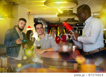 Man bartender shaking cocktail mixer for young people 87374024
