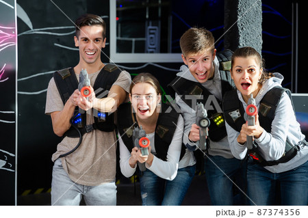 Joyful people posing with laser guns Joyful people posing with laser guns 87374356