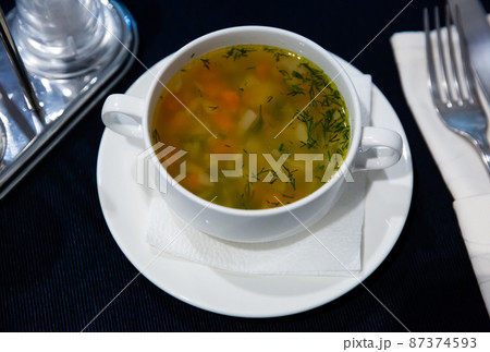 White tureen with thick vegetable soup in chicken broth White tureen with thick vegetable soup in chicken broth 87374593