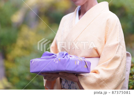 和服で風呂敷包みを持ち庭に立つ女性 和服で風呂敷包みを持ち庭に立つ女性 87375081