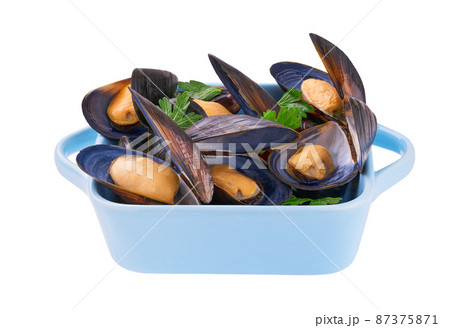 Boiled mussels shells lie with sauce and parsley on the plate isolated on white background. 87375871
