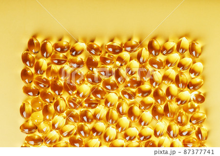Capsules in a shell with liquid vitamin D3 on a yellow background and a place for text 87377741
