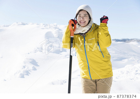 笑顔で雪かきをする若い女性 87378374