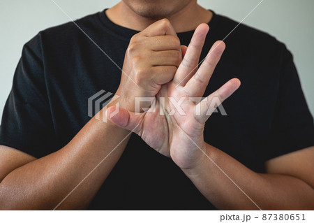 Office syndrome concept. Index finger is massaged and stretched after working. Close up shot isolate on blue background. Forehand view. 87380651