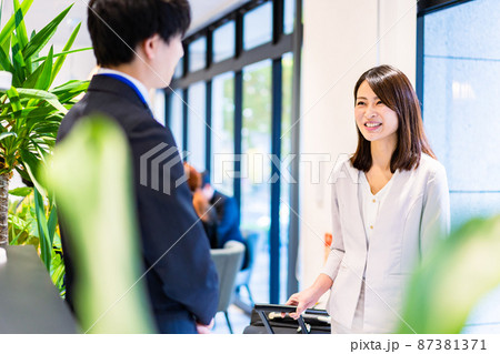 フロントでホテルのチェックインをする若いビジネスウーマン フロントでホテルのチェックインをする若いビジネスウーマン 87381371