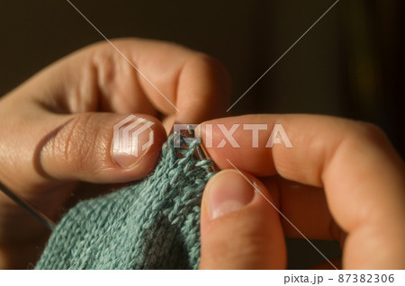 Close-up hand knitting. Hobbies, handicrafts. Knitting warm clothes from woolen fine yarn by hand on metal needles. Selective focus Close-up hand knitting. Hobbies, handicrafts. Knitting warm clothes from woolen fine yarn by hand on metal needles. Selective focus 87382306