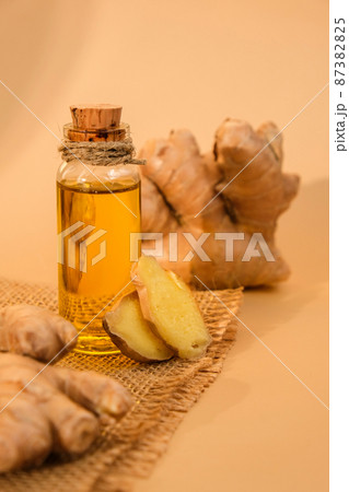 Glass bottle of essential ginger oil, ginger root on beige background. Healthy food eating concept. Zingiber officinale Essential oil. Natural cosmetics ingredients for skincare, body and hair care 87382825