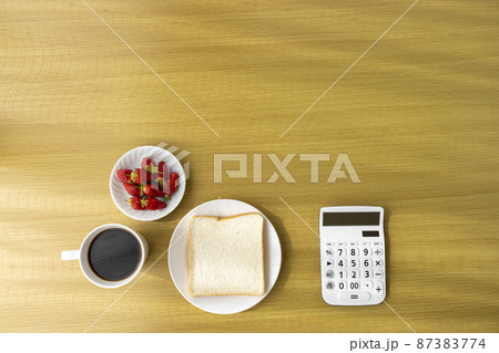 電卓と朝食（食パン、苺、コーヒー）。食費のイメージ 87383774