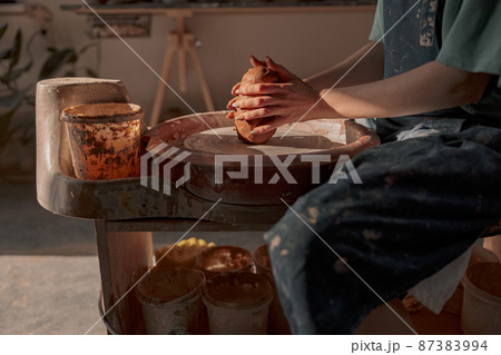 Young potter working on pottery wheel in workshop 87383994