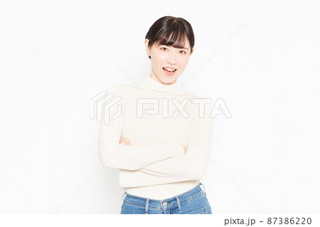 白い背景の前に立って腕組みをしている笑顔の女性 87386220