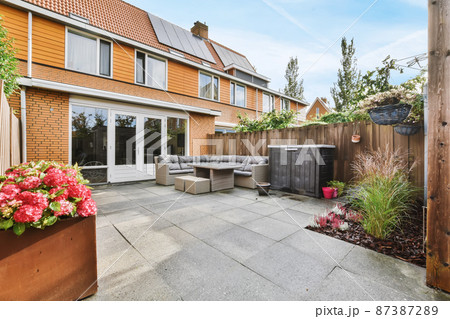 Delightful courtyard of the house with a soft sofa and a wicker table 87387289