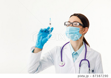 A nurse holds a syringe before giving an injection. The concept of vaccination. A nurse holds a syringe before giving an injection. The concept of vaccination. 87387290