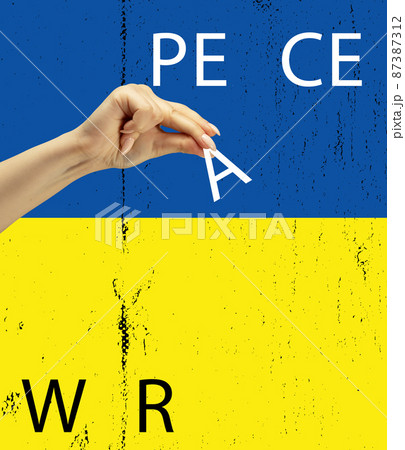Conceptual collage with human hand holding letter a on blue yellow flag of Ukraine background. No war, peace in the world. 87387312