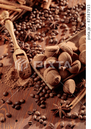 Chocolate truffles and a wooden spoon with cacao powder. 87387915