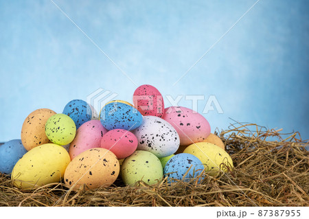 Colorful easter eggs on dry grass on sky blue background 87387955