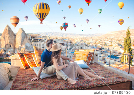 Happy young couple during sunrise watching hot air balloons in Cappadocia, Turkey Happy young couple during sunrise watching hot air balloons in Cappadocia, Turkey 87389450