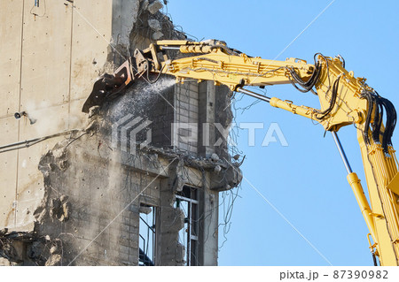 老朽化した公共建造物の解体作業をする重機 87390982