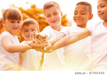 Group of children joining hands in park on sunny day. Volunteering with kids 87392450