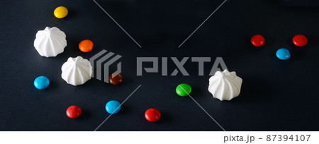 Meringues and chocolate dragee on a black background. Free space for text. 87394107