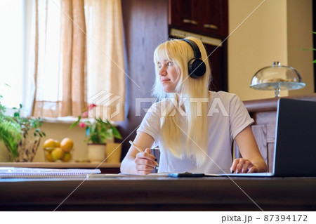 Teenage female student studying at home using a laptop. 87394172