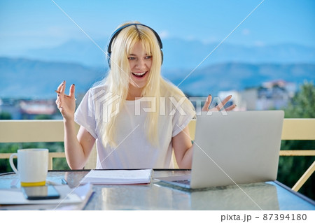 Teenage female student in headphones studying online, using laptop for video conference 87394180