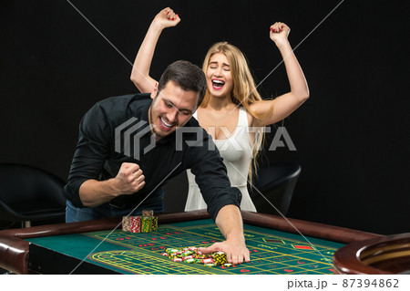 Young couple celebrating win at roulette table in casino. Young couple celebrating win at roulette table in casino. 87394862