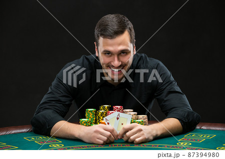 Happy poker player winning and holding a pair of aces Happy poker player winning and holding a pair of aces 87394980