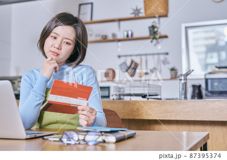 預金通帳を見つめて老後を考えるエプロン姿の若い女性 預金通帳を見つめて老後を考えるエプロン姿の若い女性 87395374
