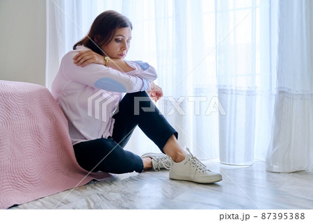 Sad middle aged depressed woman sitting on the floor in the bedroom. 87395388