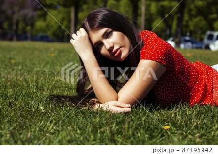 pretty young woman in red dress smiling cheerful in green park on summer sunny day, lifestyle people concept 87395942