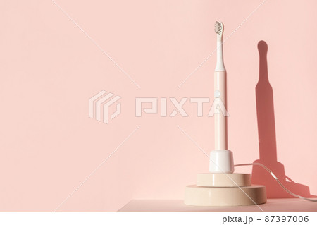 New modern ultrasonic toothbrush. Dental care supplies on cylinder podium on pink pastel background. Oral hygiene, dental and gum health, healthy teeth. Dental products  87397006