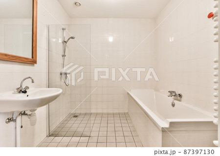 Bathroom in a minimalist style with wall tiles and a large bathtub Bathroom in a minimalist style with wall tiles and a large bathtub 87397130