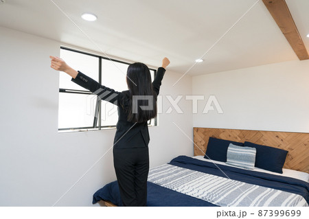 ベットルームで伸びをしているスーツを着たビジネスウーマン ベットルームで伸びをしているスーツを着たビジネスウーマン 87399699