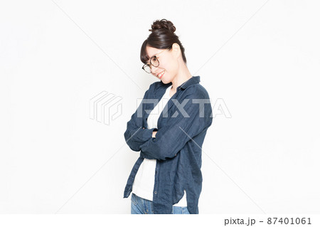 白い背景の前に立って腕組みしている眼鏡をかけている女性 87401061