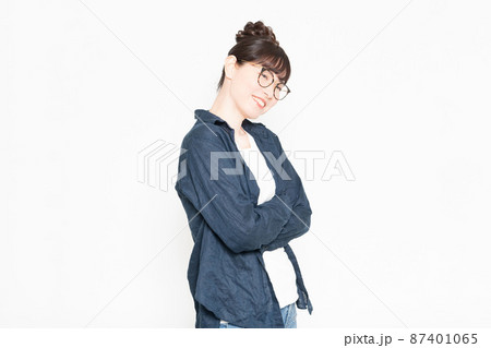白い背景の前に立って腕組みしている眼鏡をかけている女性 87401065