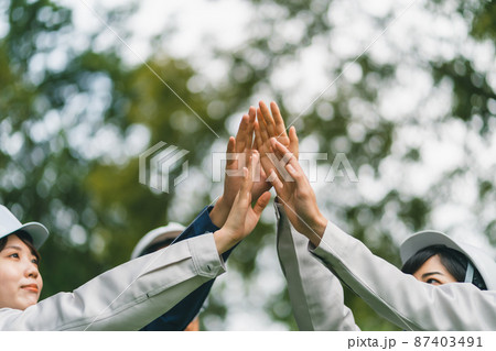 ヘルメット着用の作業員のハイタッチ 87403491