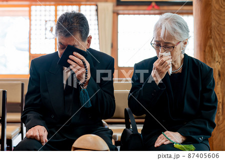 お葬式で泣く高齢者の男女 87405606