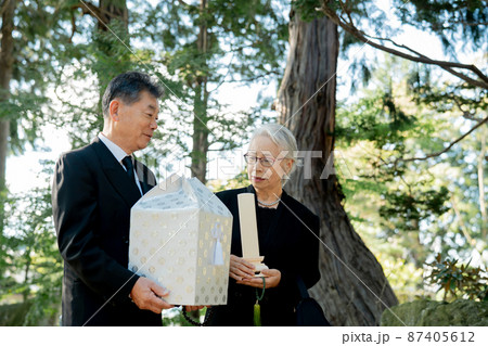 お葬式で火葬した遺骨を持つ日本人の高齢者夫婦 87405612