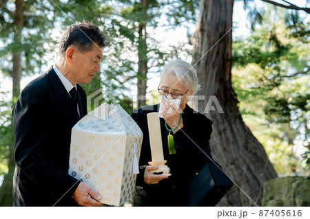 お葬式で火葬した遺骨を持つ日本人の高齢者夫婦 87405616