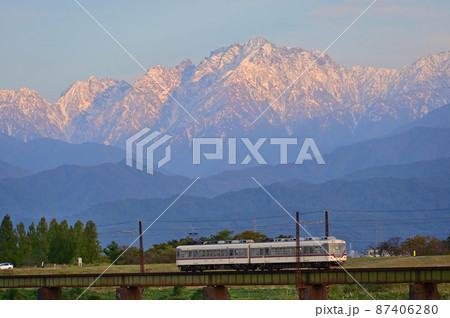 夕日に染まる立山連峰と鉄道 87406280