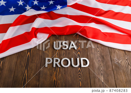 words USA proud laid with silver metal letters on brown wooden surface with flag of United States of America words USA proud laid with silver metal letters on brown wooden surface with flag of United States of America 87408283