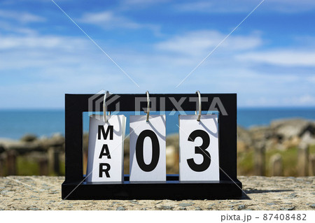 Mar 03 calendar date text on wooden frame with blurred background of ocean 87408482