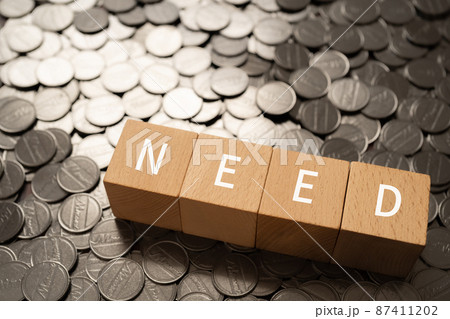 「NEED」と書かれた積み木とコイン 87411202