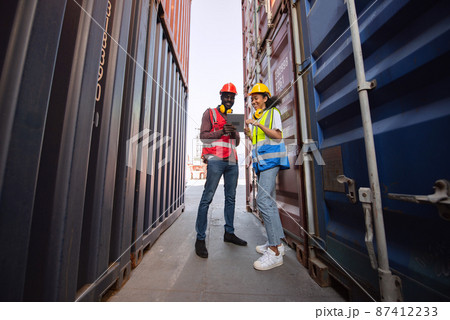 Happy two African american male and female worker using tablet and checking control loading freight containers from Cargo freight ship for import export. Happy two African american male and female worker using tablet and checking control loading freight containers from Cargo freight ship for import export. 87412233
