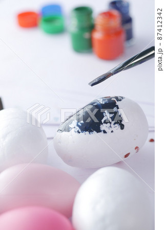 painting easter egg with a brush  87412342