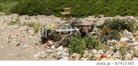 Old lobster traps and rope in a garbage pile on a beach in Rhode Island 87413365