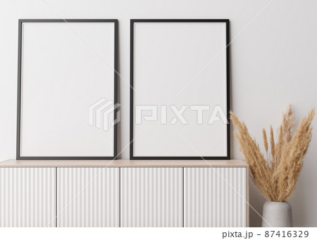 Two empty vertical picture frames standing on wooden sideboard. Mock up interior in contemporary style. Free space for picture, poster. Console, vase with pampas grass. 3D rendering. Two empty vertical picture frames standing on wooden sideboard. Mock up interior in contemporary style. Free space for picture, poster. Console, vase with pampas grass. 3D rendering. 87416329