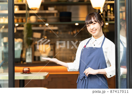 カフェの前でお客さまをお迎えする若い女性店員 カフェの前でお客さまをお迎えする若い女性店員 87417011