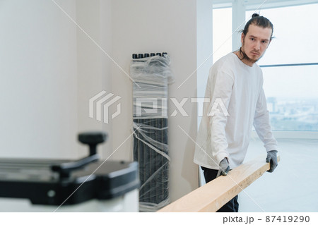 carpenter in protective gloves for working with wood on the planing machine 87419290